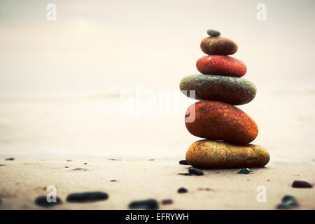 Steinen Pyramide auf Sand als Symbol für Zen, Harmonie und Balance. Ozean im Hintergrund Stockfoto