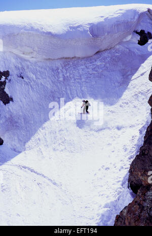 Weiblichen Snowboarder fahren unter prekären überhängenden Lippe in Pakistans schneebedeckten Berge des Karakorum. Über 4500m Stockfoto