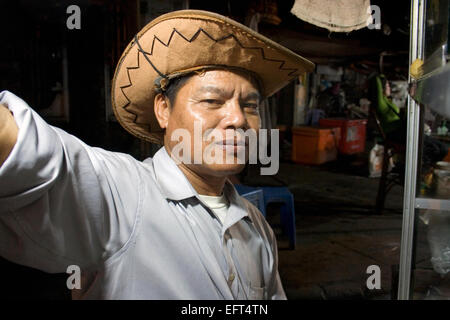 Ein Mann trägt einen Cowboyhut arbeitet an einem mobilen Straßenküchen Wagen nachts auf einer Stadtstraße in Kampong Cham, Kambodscha. Stockfoto
