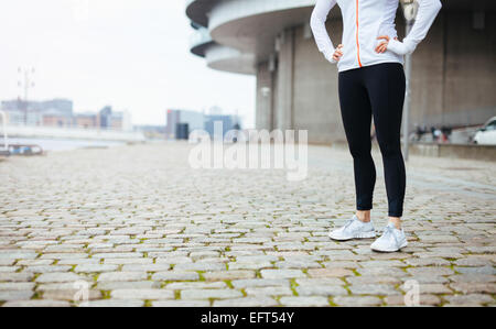 Zugeschnittenen Schuss einer jungen Frau, die auf städtischen Straßen Weile heraus für einen Lauf in der Stadt stehen. Fitness Frauen stehen mit ihren Händen. Stockfoto