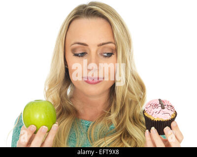 Junge Frau mit und Vergleichen von Kuchen und Obst Stockfoto