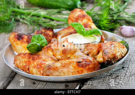 Gebackene Hühnerflügel mit Sauce auf Holztisch, Nahaufnahme Stockfoto