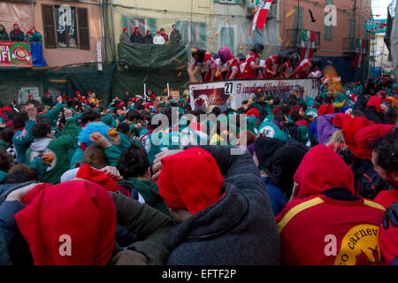 Menschenmassen umgeben einen Wagen während einer intensiven Orange Kampf am Karneval von Ivrea zu werfen. Stockfoto