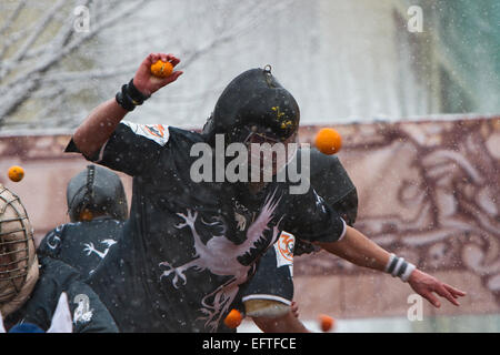 Eine orange Werfer kämpfen aus einem Warenkorb während eines Schneefalls als Teil der Schlacht der Orangen am Karneval von Ivrea. Stockfoto