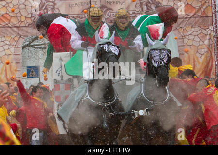 Orange-Werfer kämpfen aus einem Warenkorb während eines Schneefalls als Teil der Schlacht der Orangen am Karneval von Ivrea. Stockfoto