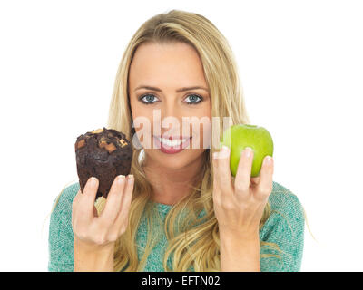 Junge Frau mit und Vergleichen von Kuchen und Obst Stockfoto