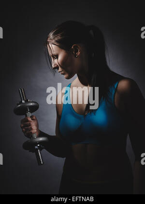 Gewichtheben, junge Frau tragen Sportswear und sie ausüben, Studioaufnahme, dunklen Hintergrund Stockfoto