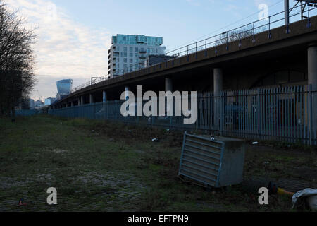 Szene bei Abenddämmerung Suche entlang der DLR-Bahnlinie in Richtung Tower Gateway und darüber hinaus auf der City of London, UK. Das ist ziemlich viel Brachland im Besitz von Transport for London die Garagen unter den obenliegende Schiene Linien trennen. Stockfoto