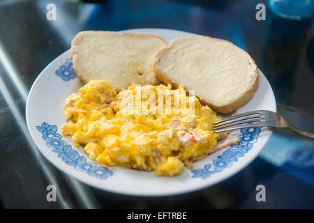 Rührei mit Schinken und zwei Scheiben Brot auf einem Teller Stockfoto