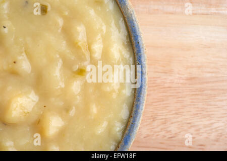 Enge Draufsicht einer Portion Kartoffel-Lauch-Suppe in eine Schüssel auf einer hölzernen Tischplatte. Stockfoto