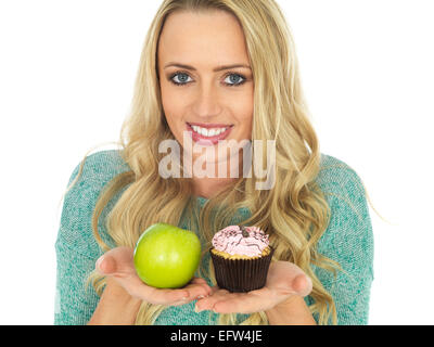 Junge Frau mit und Vergleichen von Kuchen und Obst Stockfoto