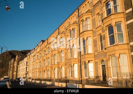 Reihenhäuser entlang der Victoria Terrasse, mit Blick auf Strand und Cardigan Bay bei Sonnenuntergang, Ceredigion, Mid Wales, Aberystwyth, Wales. Stockfoto