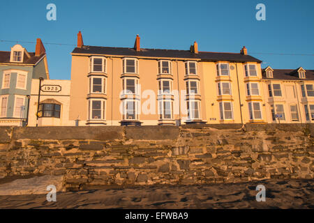 Reihenhäuser entlang der Victoria Terrasse, mit Blick auf Strand und Cardigan Bay bei Sonnenuntergang, Ceredigion, Mid Wales, Aberystwyth, Wales. Stockfoto