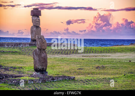 Zwei Statuen der Moai auf der Osterinsel mit einem lila Sonnenuntergang hinter Ihnen Stockfoto