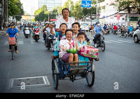 Schule Kinder reiten Fahrradrikscha auf einer belebten Straße, Ho-Chi-Minh-Stadt (Saigon), Vietnam. Stockfoto