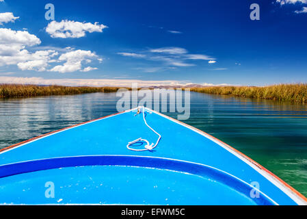 Boot auf der Durchreise Kanal mit Schilf auf beiden Seiten am Titicaca-See in der Region um Uros schwimmende Inseln in der Nähe von Puno, Peru Stockfoto