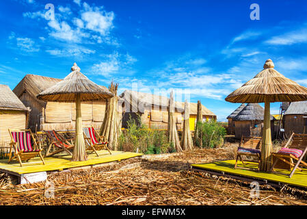 Häuser und Sonnenschirme gemacht aus Schilf auf schwimmenden Inseln der Uros am Titicaca-See in der Nähe von Puno, Peru Stockfoto