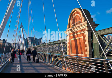 Touristen auf der Hungerford Bridge, central London, neben dem Bahnübergang Bahnhof Charing Cross im Hintergrund. Stockfoto