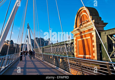 Touristen auf der Hungerford Bridge, central London, neben dem Bahnübergang Bahnhof Charing Cross im Hintergrund. Stockfoto