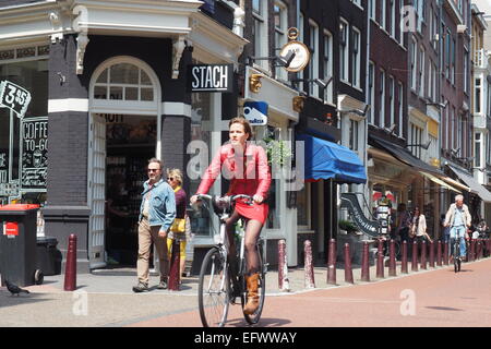 Eine Frau im roten Outfit Radfahren in Amsterdam. Stockfoto