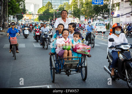 Schule Kinder reiten Fahrradrikscha auf einer belebten Straße, Ho-Chi-Minh-Stadt (Saigon), Vietnam. Stockfoto