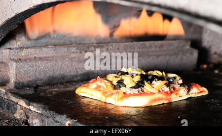 die Pizza wird im Ofen über dem offenen Feuer zubereitet. Stockfoto