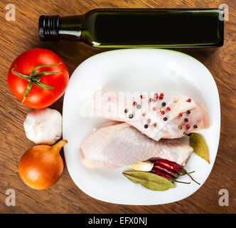 Hähnchenschenkel auf dem Teller mit Gewürzen und Gemüse, einen hölzernen Hintergrund Stockfoto