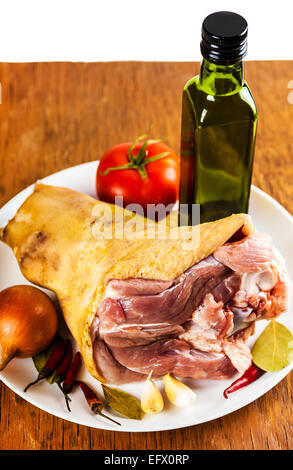 rohes Schweinefleisch Schaft auf einem Teller mit Gewürzen und Gemüse, einen hölzernen Hintergrund Stockfoto