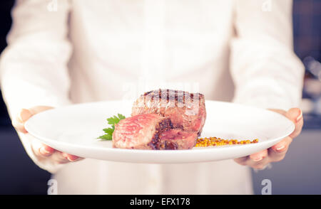 Koch hält eine Schüssel mit Medaillons in Händen Stockfoto