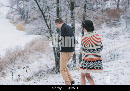 Braut und Bräutigam zu Fuß bergab Hand in Hand im Winterwald Stockfoto