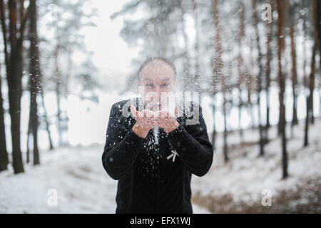 Bräutigam Schneetreiben von seinen Händen im tief verschneiten Winterwald Stockfoto