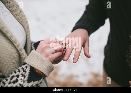 Braut Bräutigam seine Finger bei Winterhochzeit Hochzeit Ring aufsetzen Stockfoto