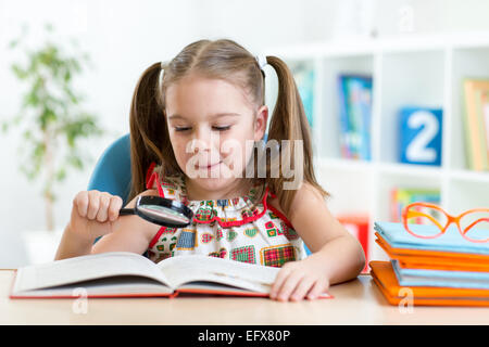 Erstaunt Kind Blick durch ein Vergrößerungsglas mit Buch Stockfoto