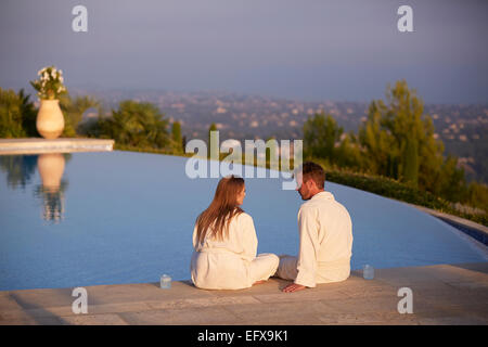 Junges Paar in Roben entspannend am Pool in Südfrankreich Stockfoto