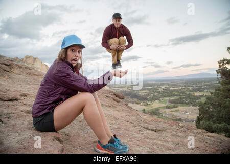 Junger Mann springt Luft einerseits Top junge Womans Smith Rock, Oregon, USA Stockfoto