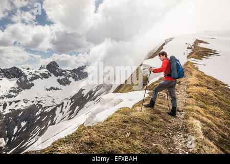 Junge männliche Berg Wanderer auf der Suche von Bergrücken in den Bayerischen Alpen, Oberstdorf, Bayern, Deutschland Stockfoto