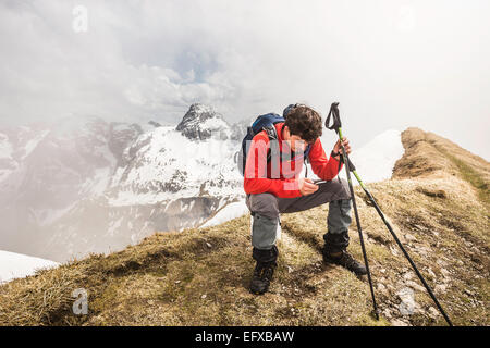 Junge männliche Berg Trekker SMS auf Smartphone im Allgäu, Oberstdorf, Bayern, Deutschland Stockfoto