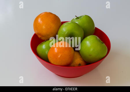 Nahaufnahme von frische grüne Äpfel und Orangen in einer roten Schale Stockfoto