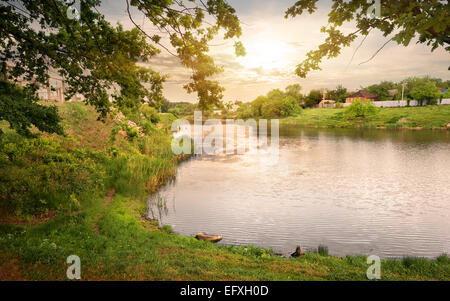 Sonnenuntergang über See in der Nähe eines Dorfes Stockfoto