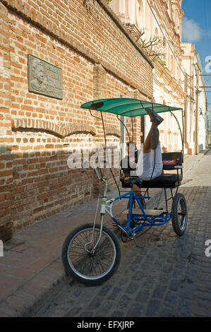 Vertikale Porträt eines Bicitaxi Arbeitnehmers eine Pause in Camagüey, Kuba. Stockfoto