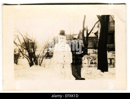 12. Dezember 2014 - Kanada - ca. 1940er Jahre: Reproduktion eines antiken Fotos zeigt Mann posiert neben einen Schneemann auf dem Hintergrund der schneebedeckten Straßen (Credit-Bild: © Igor Golovniov/ZUMA Wire/ZUMAPRESS.com) Stockfoto