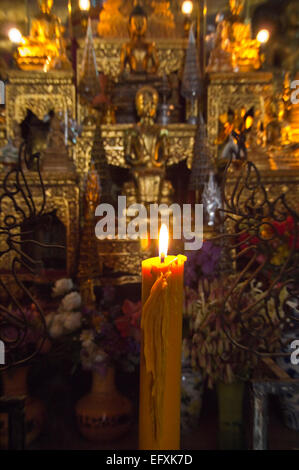 Vertikale Nahaufnahme einer brennenden votive Kerze am Wat Mai Suwannaphumaham oder das neue Kloster in Luang Prabang. Stockfoto