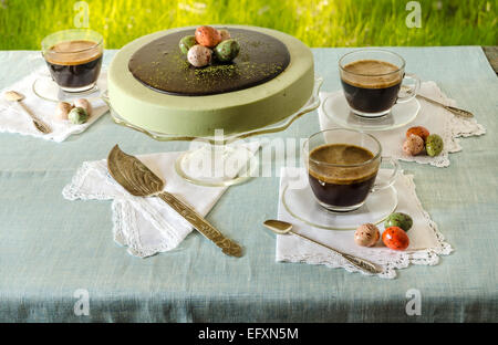 Ostertisch mit Tee Matcha Käsekuchen und schwarzen Kaffee auf Hintergrund von grünem Rasen Stockfoto