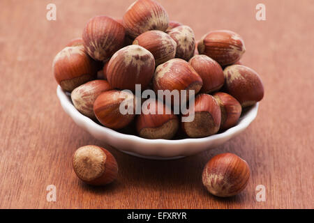 Haselnüsse in einer Schüssel auf hölzernen Hintergrund Stockfoto
