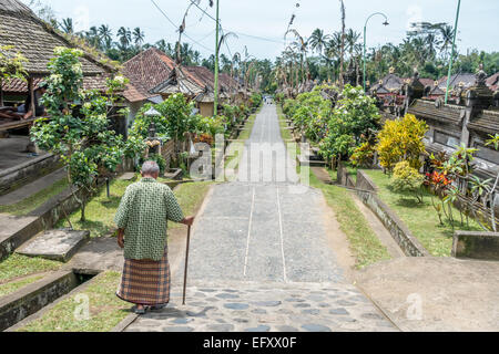 Ein Alter Mann geht durch die Gasse auf der Community-Based Tourism Village Penglipuran (Desa Wistata Penglipuran Berbasis Masyarakat) Stockfoto