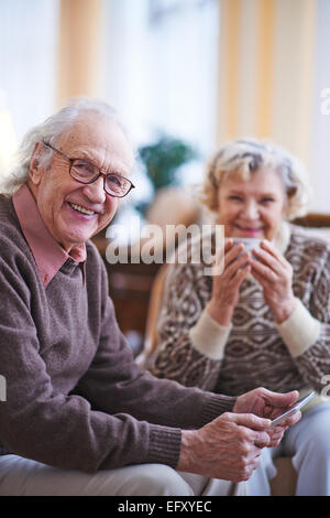 Ältere Mann mit Touchpad Blick in die Kamera beim Ausruhen zu Hause am Wochenende Stockfoto