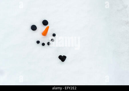 Glücklich Schneemann Gesicht mit einem großen Kohle-Herz im Schnee Stockfoto