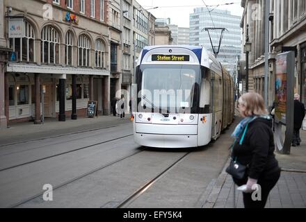 Eine Frau wartet, um die Straße zu überqueren, während ein Nottingham Expressverkehr Straßenbahn Heads für station street England UK Stockfoto