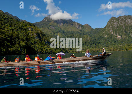 Ein Boot mit Touristen segelt auf dem Meerwasser im Hintergrund der Landschaft der Insel Seram in der Nähe des Dorfes Saleman in Nord-Seram, Zentral-Maluku, Stockfoto