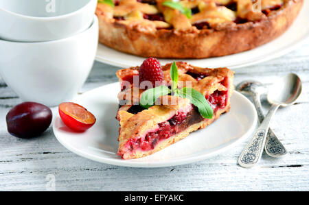 Stück hausgemachten Kuchen mit Pflaumen und dunkler Schokolade, dekoriert mit frischen Himbeeren und Bergamotte Stockfoto